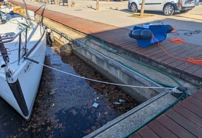 DPOL sur le quai, à côté d'un port dont la surface de l'eau est recouverte de déchets.